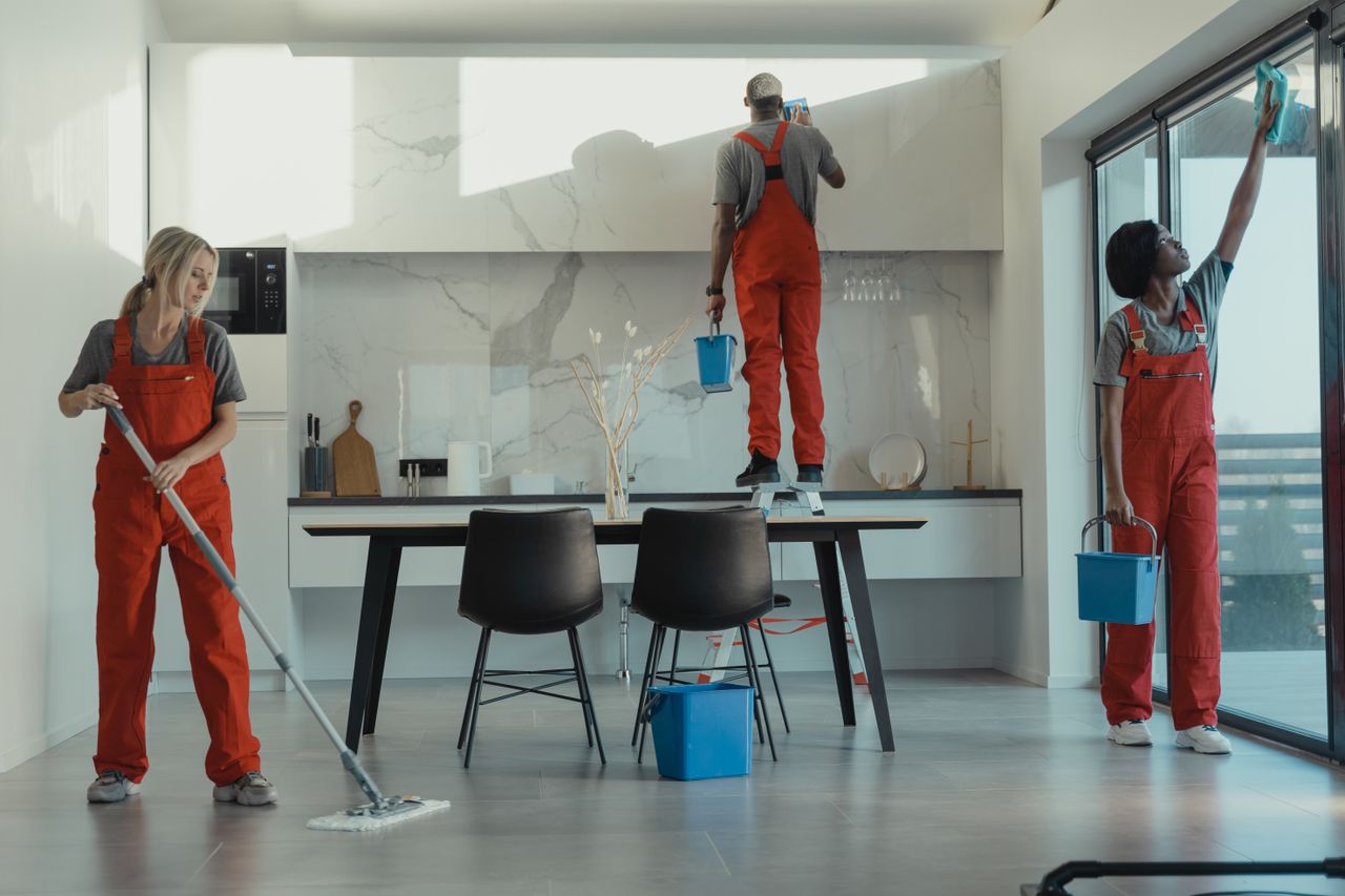 services-01 Group of cleaners in red uniforms mopping and wiping glass in a modern dining room.